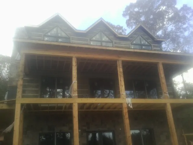 Dormers and porch framing on a large log home under construction — Roof Coating work by our crew in Medaryville
