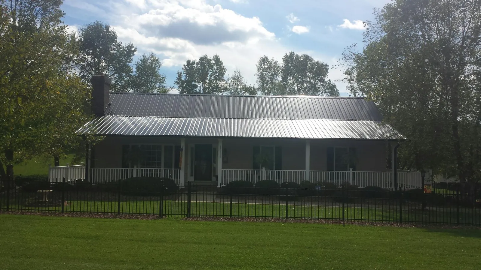 Gray metal roof on a brick ranch with a full width front porch — Gutter Guard Installation work by our crew in Medaryville