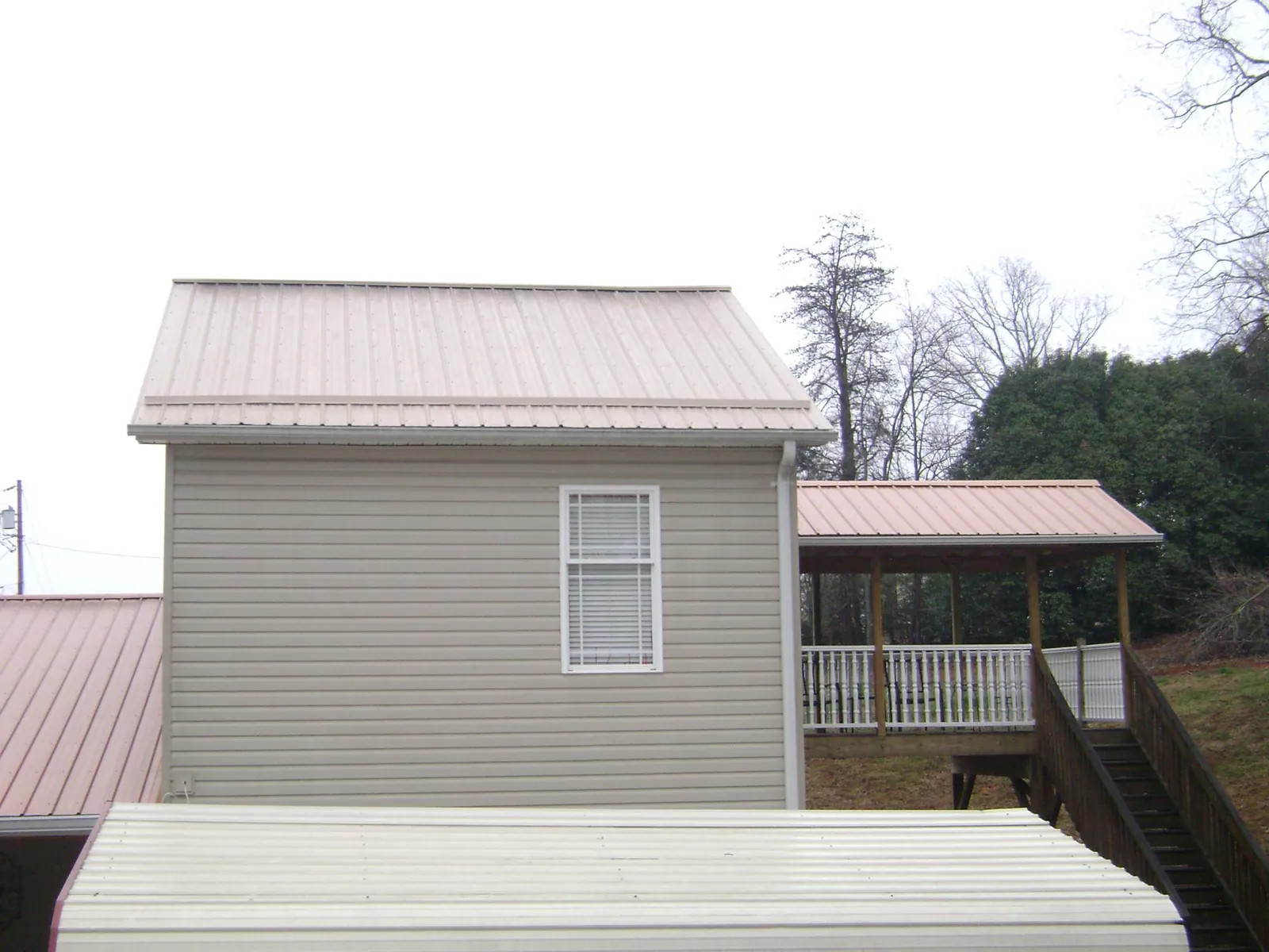 Tan metal roofs on a two story addition and attached porch, from a Roof Replacement job in Medaryville