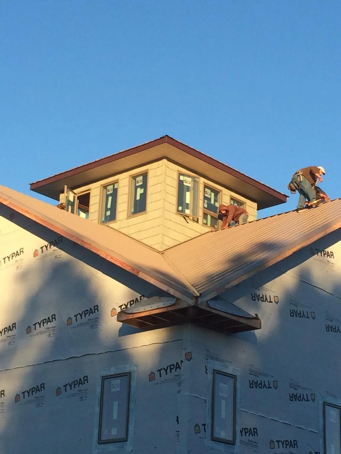 Roofers working around a rooftop cupola on a new metal roof at sunset — Roof Waterproofing in Medaryville by Roofing Brothers